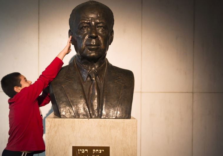 A boy touches the bust of Yitzhak Rabin before a rally commemorating the 20th anniversary of his assassination in Tel Aviv, October 31