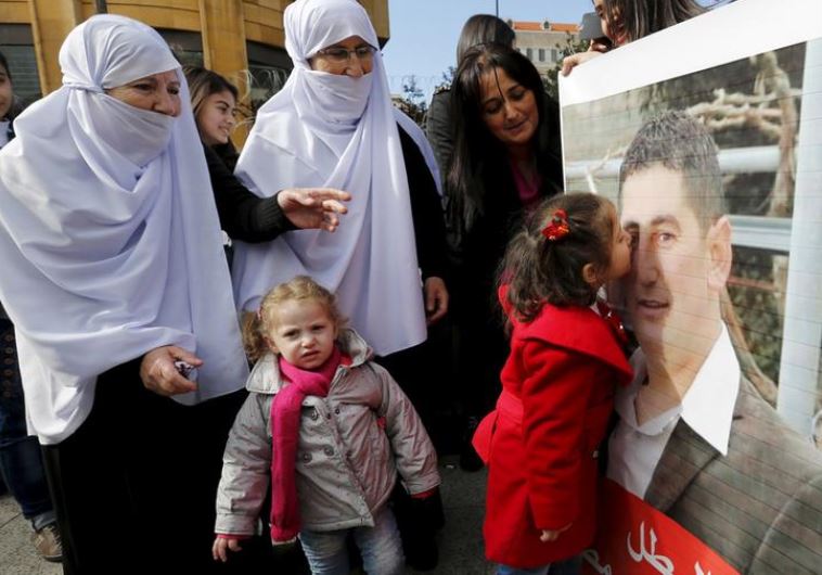 The daughter of Druze policeman Wael Hamzeh Homs, who was captured in Arsal by the al Qaeda-linked Nusra Front, kisses his picture as relatives react in celebration for his release, outside a tent that was erected last year during an open-ended sit-in near the government palace in downtown Beirut, D