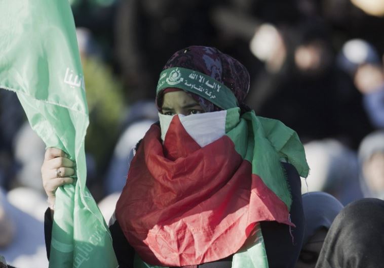 A Palestinian woman covering her face with her national flag takes part in an anti-Israel rally in Gaza City