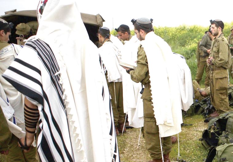Orthodox infantry soldiers of the Netzah Yehuda Battalion pray in the field