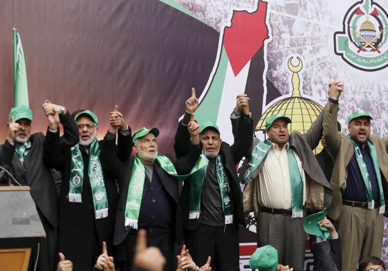 Hamas leaders (top) join hands as they take part in a rally marking the 28th anniversary of Hamas' founding