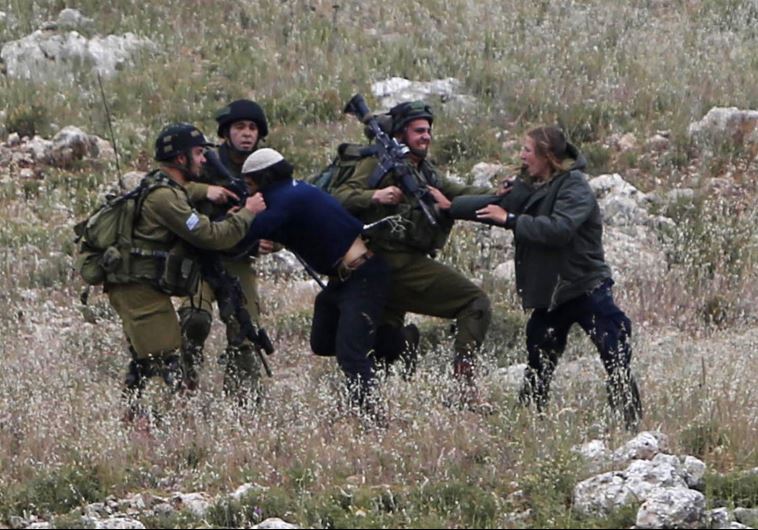 Israeli soldiers detain Jewish settlers during clashes with Palestinians near the West Bank village of Deir Jarir, near Ramallah