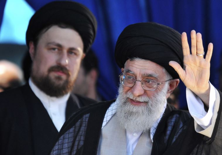 Iran's Supreme Leader Ayatollah Ali Khamenei (R) waves to his supporters as Hassan Khomeini, grandson of Iran's Late Leader Ayatollah Ruhollah Khomeini, looks on during a ceremony to mark the death anniversary of the latter
