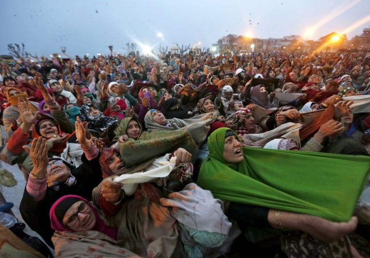 Kashmiri Muslim women raise their arms as they pray upon seeing a relic of Prophet Mohammad being displayed during the festival of Eid-e-Milad-ul-Nabi