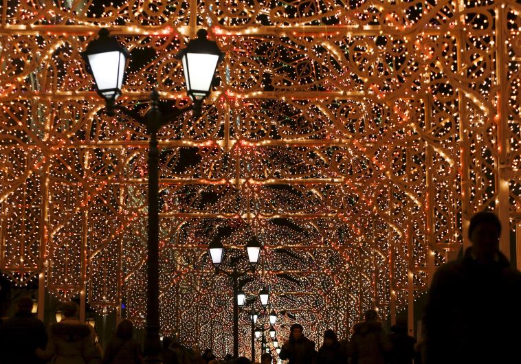 People walk along a street decorated with festive illumination lights, part of the New Year and Christmas holidays celebration, in central Moscow, Russia, December 21, 2015.