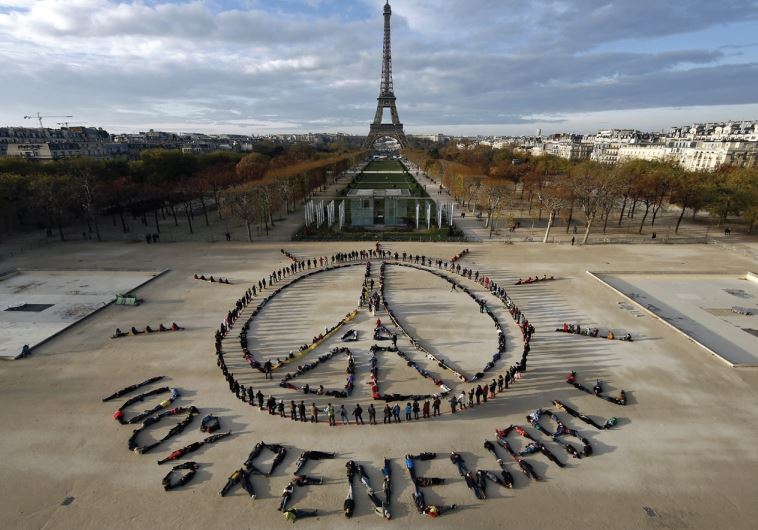 Hundreds of environmentalists arrange their bodies to form a message of hope and peace in front of the Eiffel Tower as the World Climate Change Conference 2015 convened at Le Bourget near the French capital