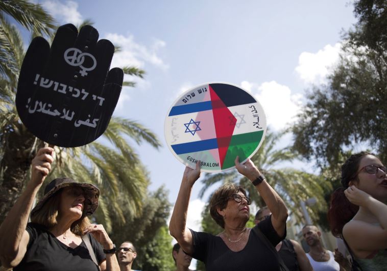 Left - wing protesters hold placards during a demonstration in Tel Aviv