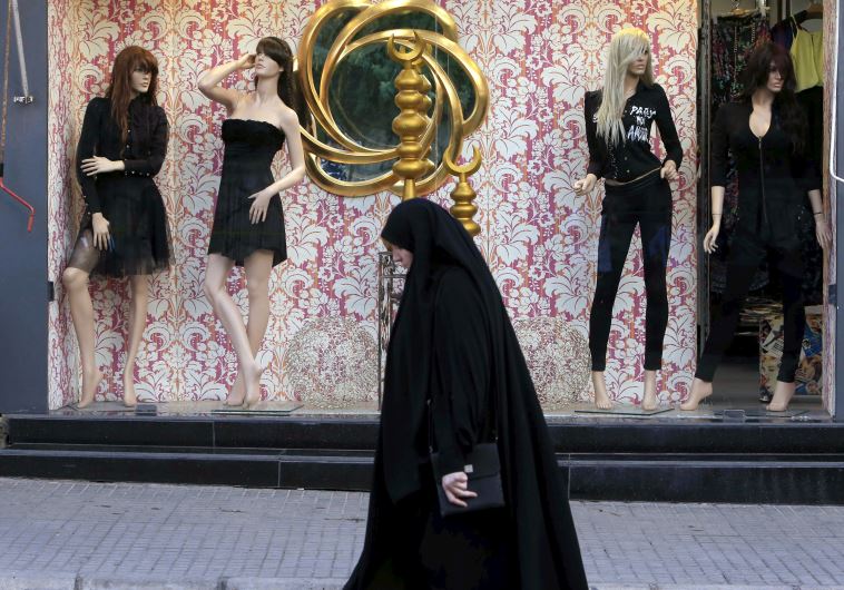 Woman wearing an abaya walks past a fashion clothing store in Lebanon