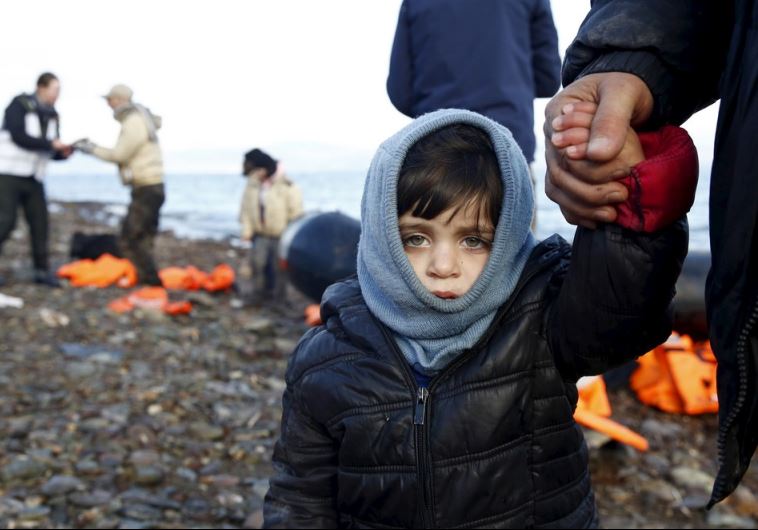 A Syrian refugee child looks on, moments after arriving on a raft with other Syrian refugees on a beach on the Greek island of Lesbos