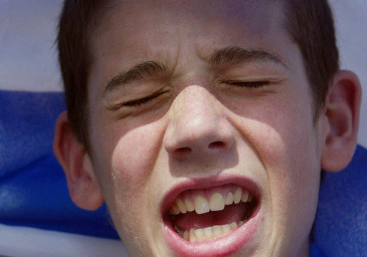 A boy sings underneath the Israeli flag at the Israel Solidarity Rally in London's Trafalgar Square