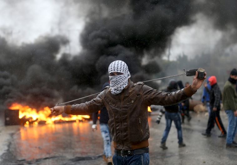 A Palestinian protester prepares his sling to hurl stones towards Israeli troops during clashes near Jenin