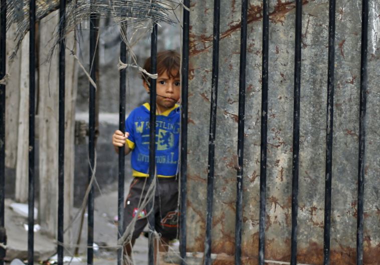 A Palestinian boy looks through the gate of his family's house at Shatti (beach) refugee camp in Gaza City 
