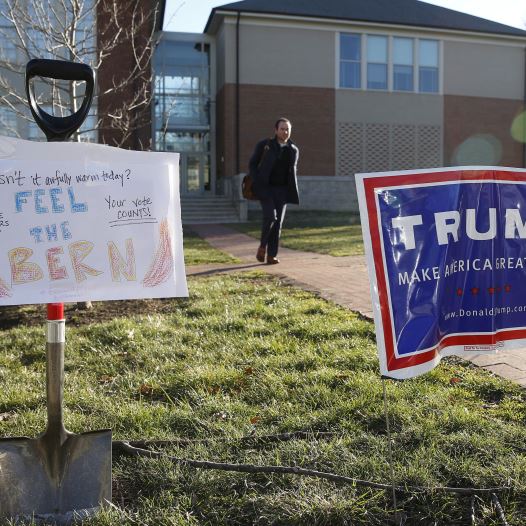 A Virginia voter is framed by a sign in support of Bernie Sanders (L) and a Donald Trump campaign sign (R) after casting his ballot in Arlington, Virginia.