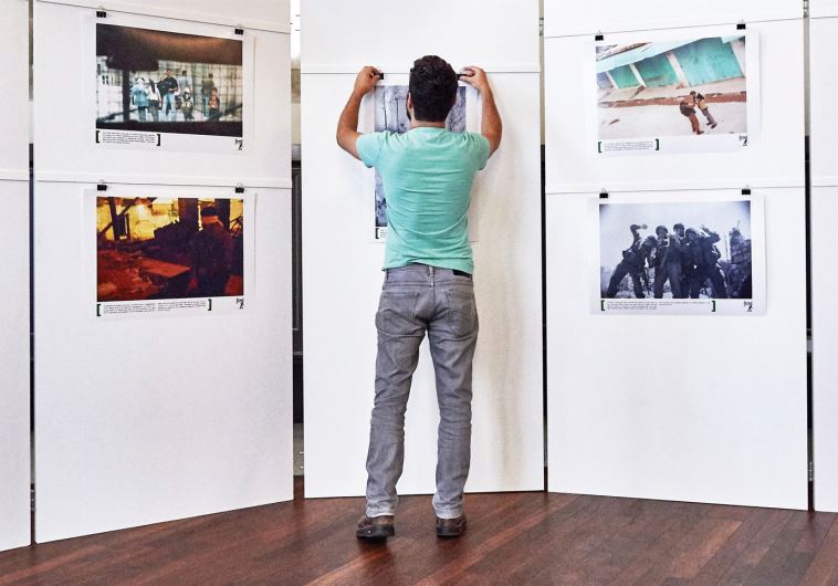 Alon Sahar hangs a photograph at a BtS exhibition at the Kulturhaus Helferei in Zurich, June 3