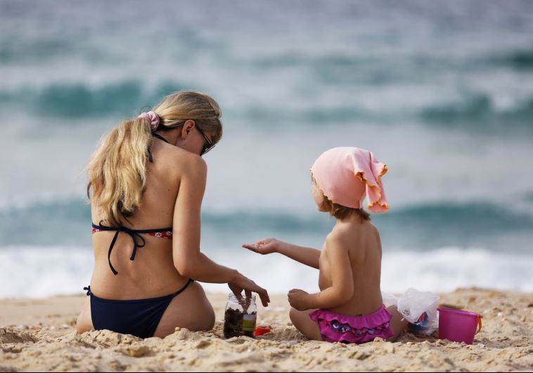 A woman and a girl sit in front of the Mediterranean at the beach in the southern Israeli city of Ashkelon