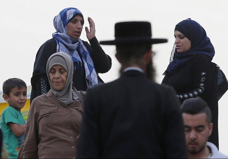 An ultra-Orthodox Jewish man walks next to Palestinian women in Jerusalem's Old City