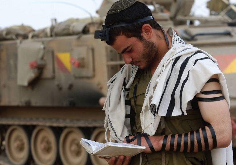 An IDF soldier prays near the Gaza border