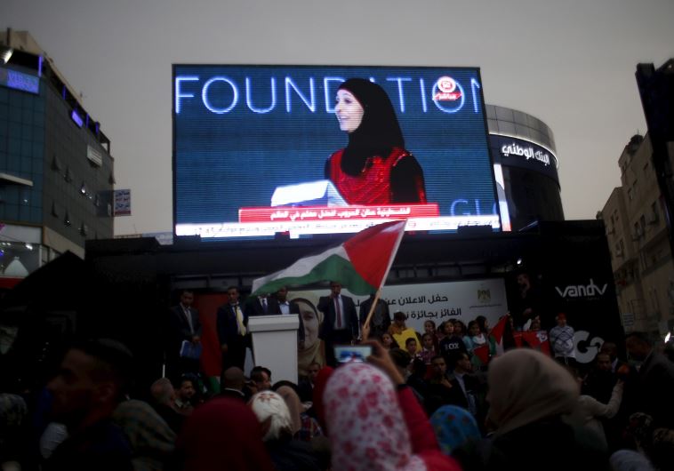 Palestinians watch on a screen in the West Bank city of Ramallah March 13, 2016 as primary school teacher Hanan al-Hroub receives the Million Dollar Teacher award. 