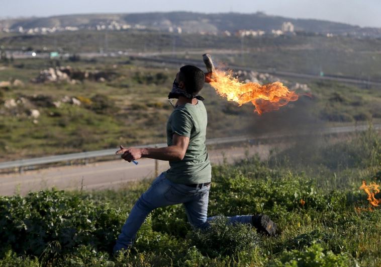 A Palestinian protester hurls a Molotov cocktail towards Israeli troops during clashes near Israel's Ofer Prison near Ramallah