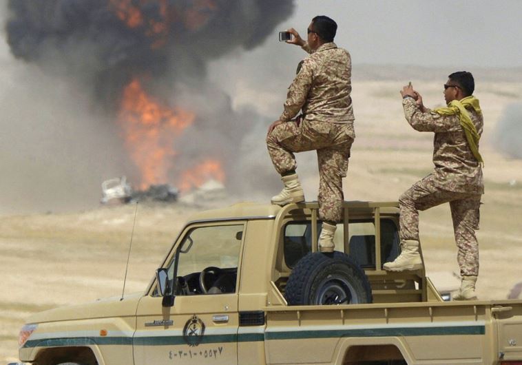 SAUDI ARABIAN soldiers take pictures as flame and smoke are seen following air bombardments during the Northern Thunder exercises, in Hafr Al-Batin, near Saudi Arabia’s border with Iraq in March.