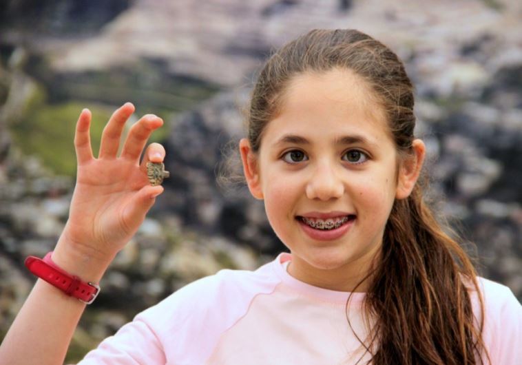 Neshama Spielman, 12, poses with the rare amulet she discovered while volunteering at the Temple Mount Sifting Project.