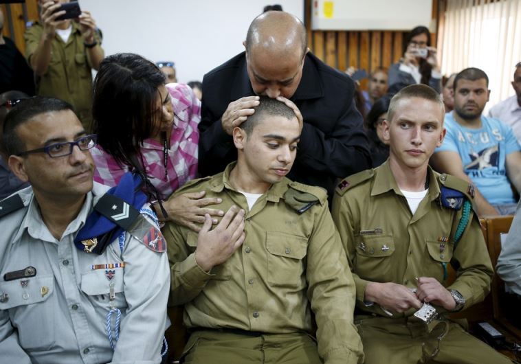 The father of Israeli soldier Elor Azaria, who is charged with manslaughter after he shot a wounded Palestinian assailant as he lay on the ground in Hebron on March 24, kisses his head in a military court