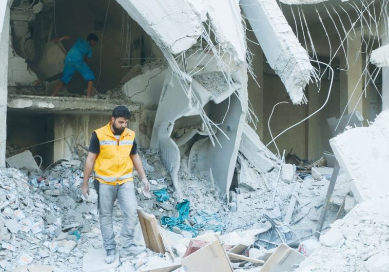 A RED CRESCENT aid worker inspects scattered medical supplies after an air strike on a medical depot in Aleppo on Saturday.