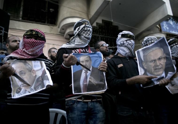 Palestinians hold knives in front of posters of Prime Minister Benjamin Netanyahu (R), Avigdor Liberman (C) and former premier Ehud Barak