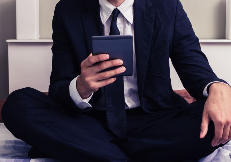 Young businessman on bed reading on tablet