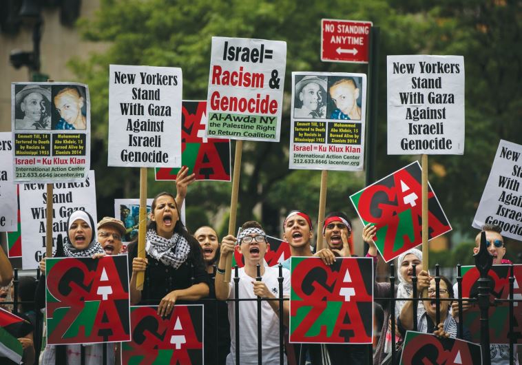 PRO-PALESTINIAN DEMONSTRATORS display signs outside New York’s City Hall in July 2014, near where a pro-Israel rally was taking place.