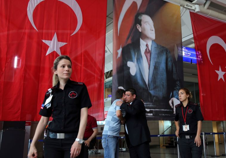 Men greet each other in front of Turkish flag and picture of modern Turkey's founder Mustafa Kemal Ataturk at Istanbul Ataturk airport, Turkey, following yesterday's blast June 29, 2016. 