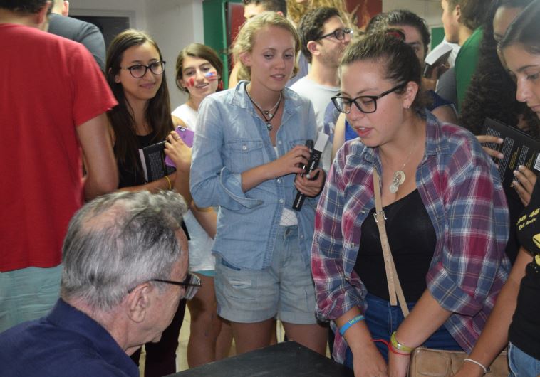 Moshe Arens signs copies of his book 'Flags over the Warsaw Ghetto' for students from Boston Onward Israel Monday night in Jerusalem.