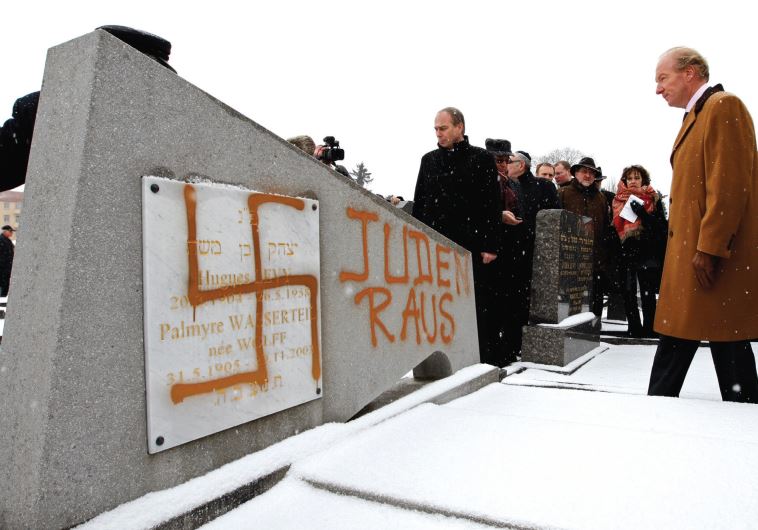 FRANCE’S THEN interior minister Brice Hortefeux walks next to a tombstone desecrated by vandals with a Nazi swastika and the slogan ‘Jews out’ in the Jewish Cemetery of Cronenbourg near Strasbourg in 2010