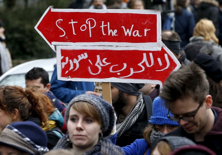 A participant of the so-called "Carnival of migrants" holds a banner as the take part in a rally to protest against racism in Berlin, Germany, March 20, 2016