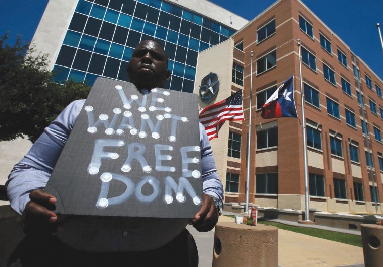 A MAN holds a sign at police headquarters earlier this week following the multiple police shootings in Dallas, Texas.
