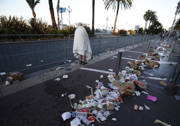 A man walks through debris scatterd on the street the day after a truck ran into a crowd at high speed killing scores celebrating the Bastille Day July 14 national holiday on the Promenade des Anglais in Nice, France, July 15, 2016.