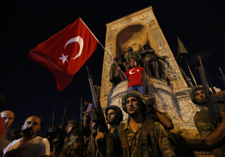 Turkish military stand guard near the the Taksim Square as people wave with Turkish flags in Istanbul, Turkey, July 16, 2016