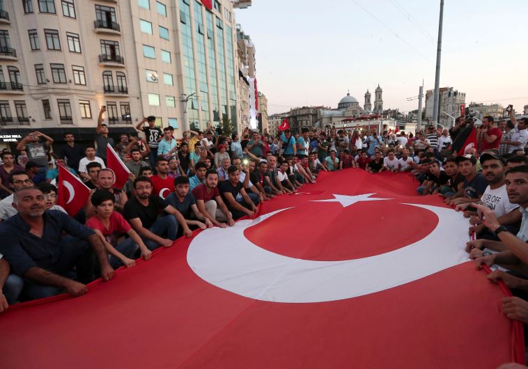 Supporters of Turkish President Tayyip Erdogan wave a huge national flag as they gather at Taksim Square in central Istanbul, Turkey, July 16, 2016.