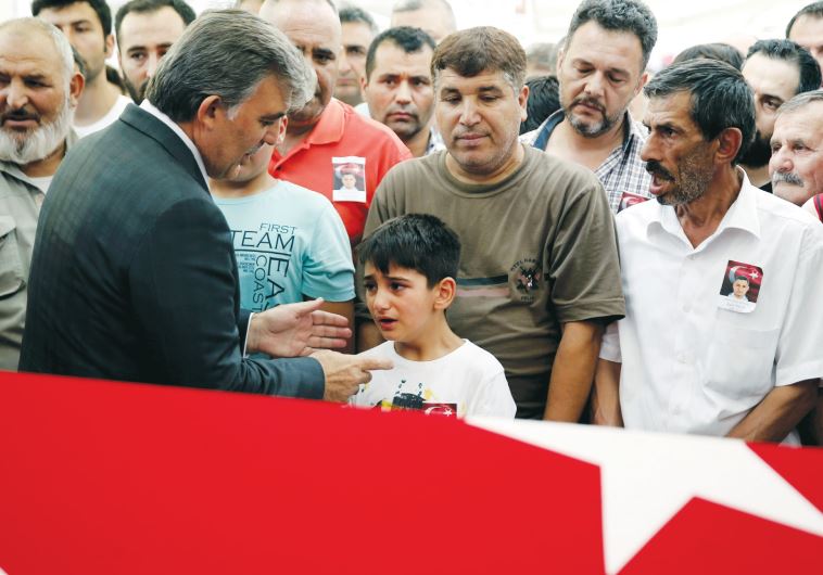 Former Turkish President Abdullah Gul (2nd L) comforts the son of a police officer killed during a thwarted coup in Turkey, on July 18 in Istanbul