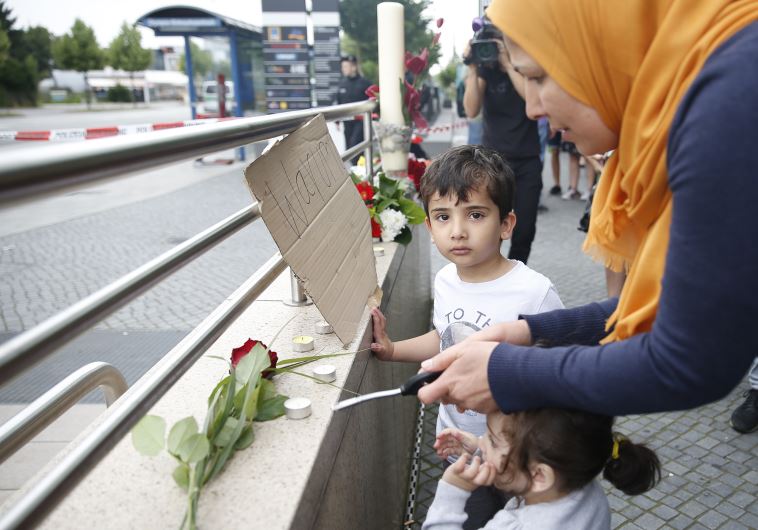 Woman lights a candle at scene of Munich shooting 
