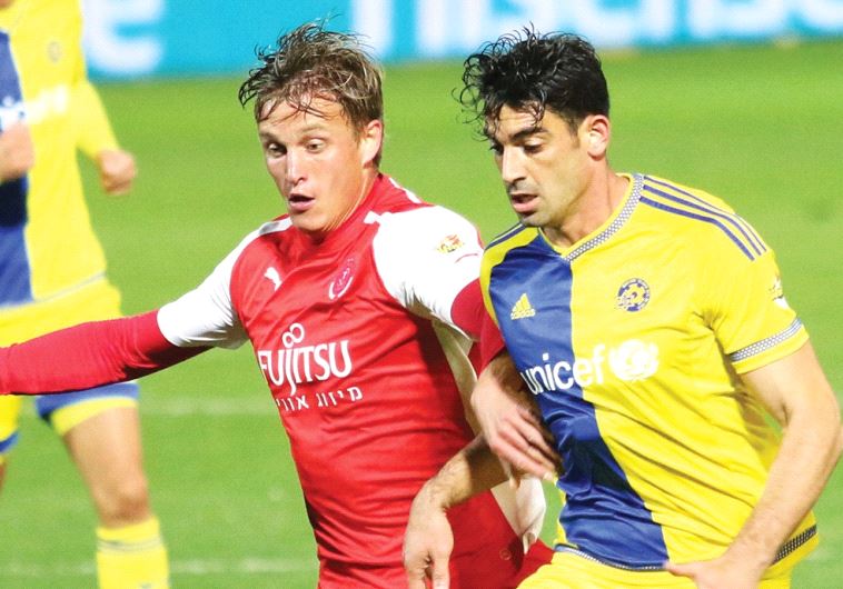 Hapoel Tel Aviv striker Aaron Schoenfeld (left, battling Maccabi Tel Aviv defender Omri Ben-Harush) is a prime example of the talent pool of American Jewish players that Israeli Premier League clubs are looking to utilize.