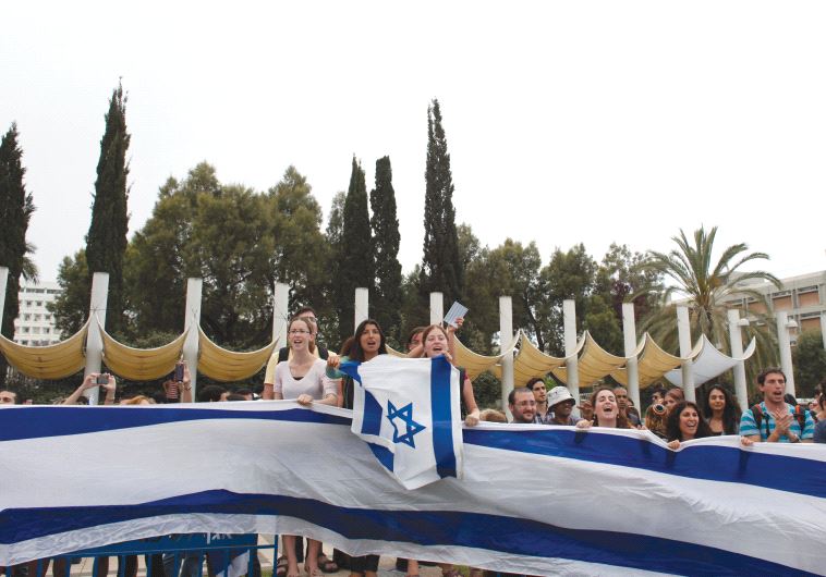STUDENTS WAVE flags at an event at Tel Aviv University.
