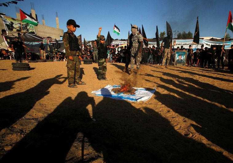 Palestinians burn an Israeli flag during a military-style graduation ceremony at a summer camp organized by the Islamic Jihad Movement in Khan Younis in the southern Gaza Strip