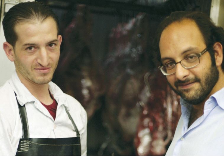 FADI KATTAN (right) makes a purchase from his butcher last week for his Hosh al-Syrian guest house in Bethlehem. (