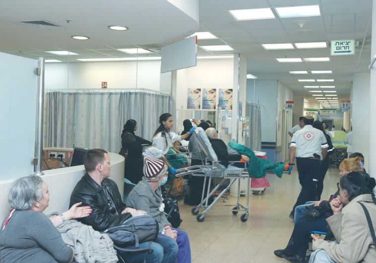 A PATIENT is brought into the emergency room at Soroka University Medical Center in Beersheba as people in the waiting room look on.