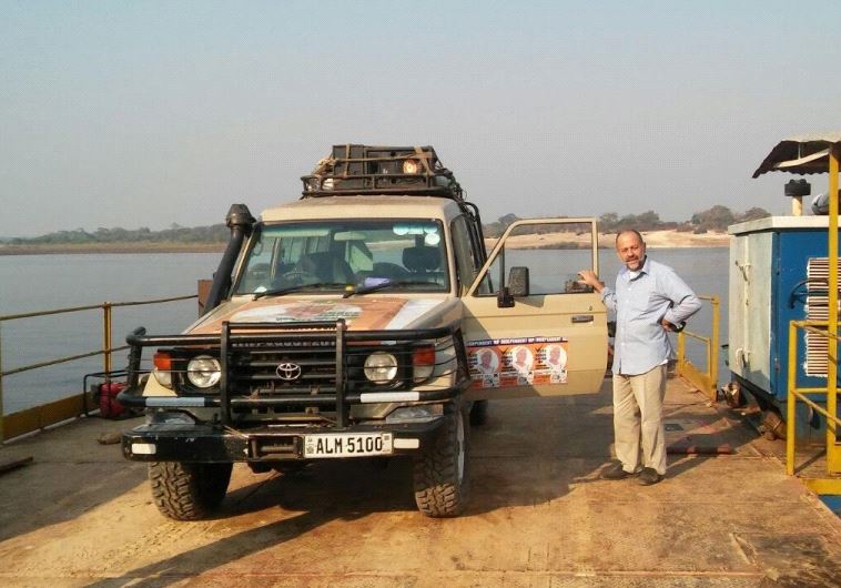 Yitzhak Efrati with his car, plastered with stickers supporting his wife, Grace Njapau