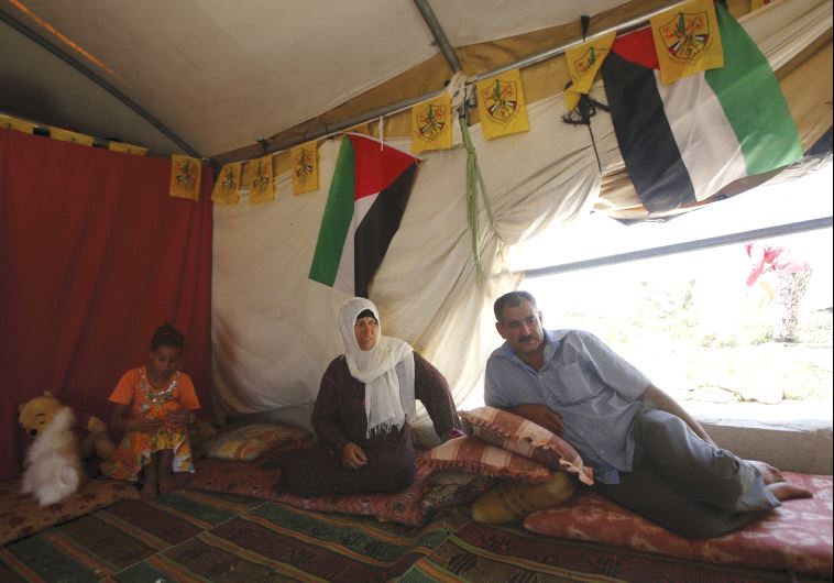 A man sits with his family inside their tent in Sussiya