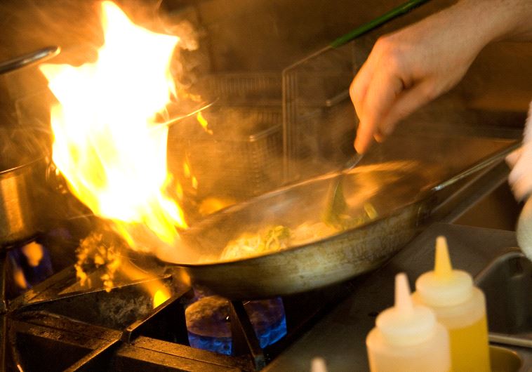Chef cooking with a flaming pan (illustrative)
