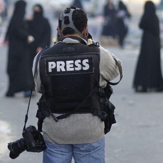 A photojournalist in a press vest [Illustrative]