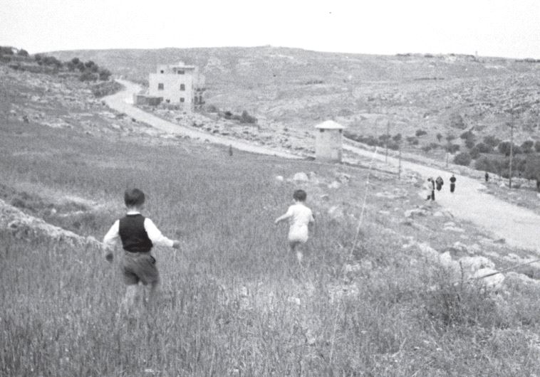 Children at play run toward a pillbox several decades ago